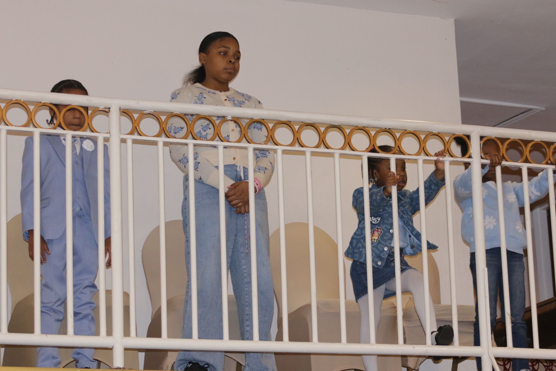 People standing behind a balcony railing, with one person centered in front and others partly visible.