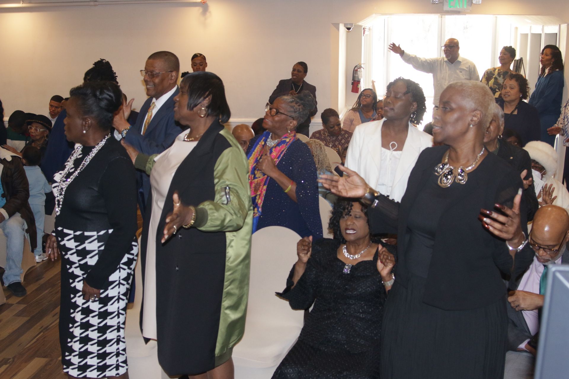People standing and clapping in a church or community hall during a gathering