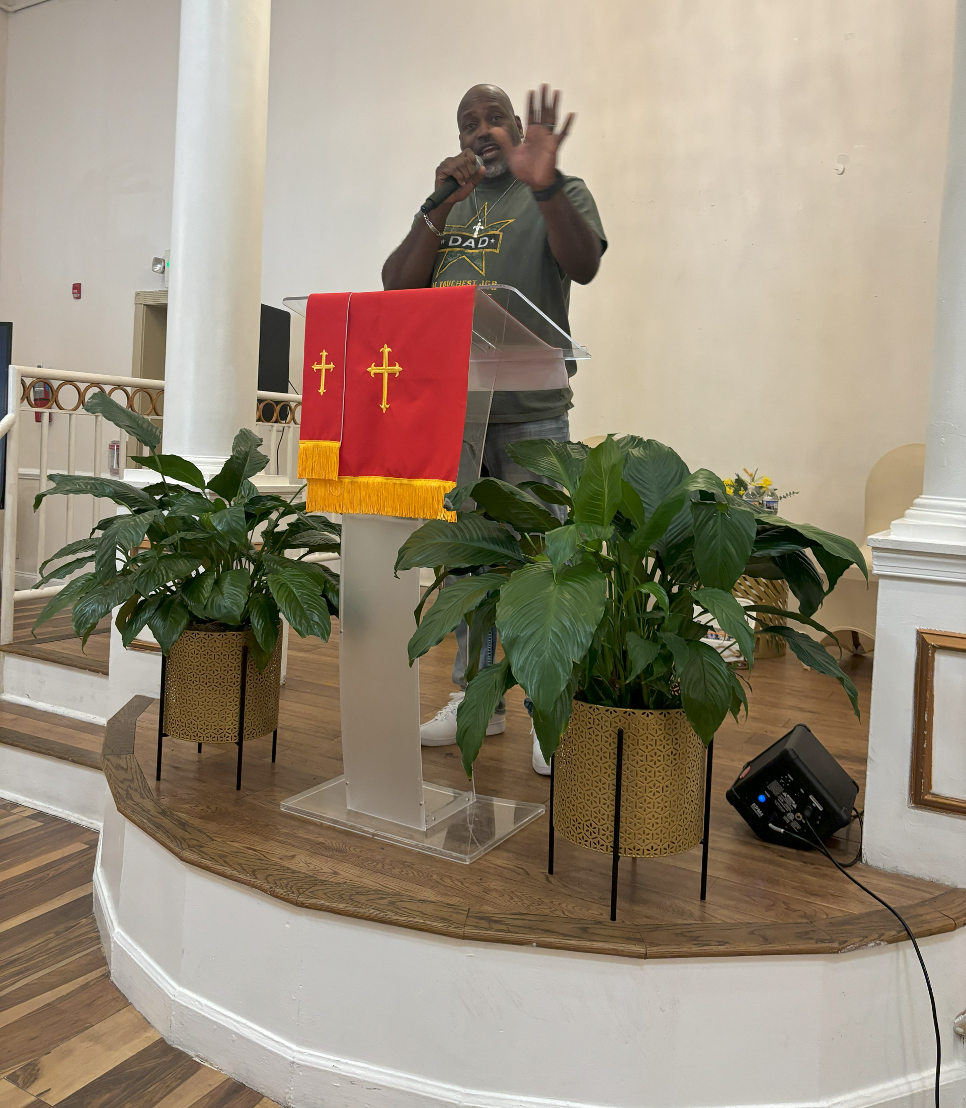 A man is standing at a podium in a church talking into a microphone.
