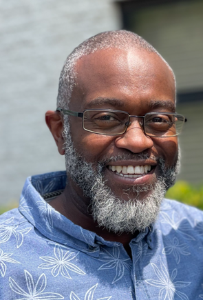 A man with a beard and glasses is smiling for the camera.