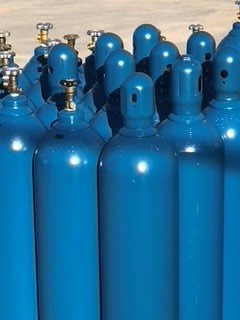 Blue compressed gas cylinders arranged closely together.