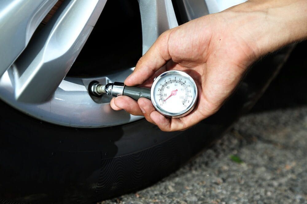 A Person Is Checking The Pressure Of A Tire With A Gauge — Dore's Goodyear Autocare Tully In Innisfail, QLD