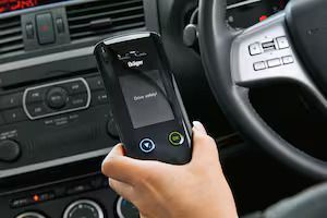 Driver Using Alcohol Breathalyzer Near the Steering Wheel — Dore's Goodyear Autocare Tully In Tully, QLD