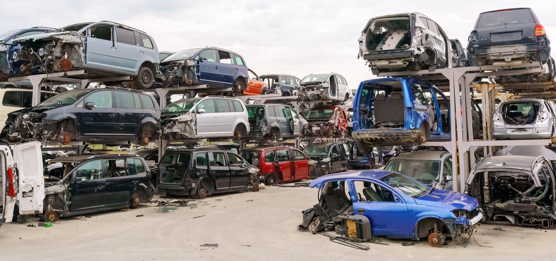 Stacks of wrecked cars piled on metal racks at a junkyard salvage lot Stacks of wrecked cars piled on metal racks at a junkyard salvage lot