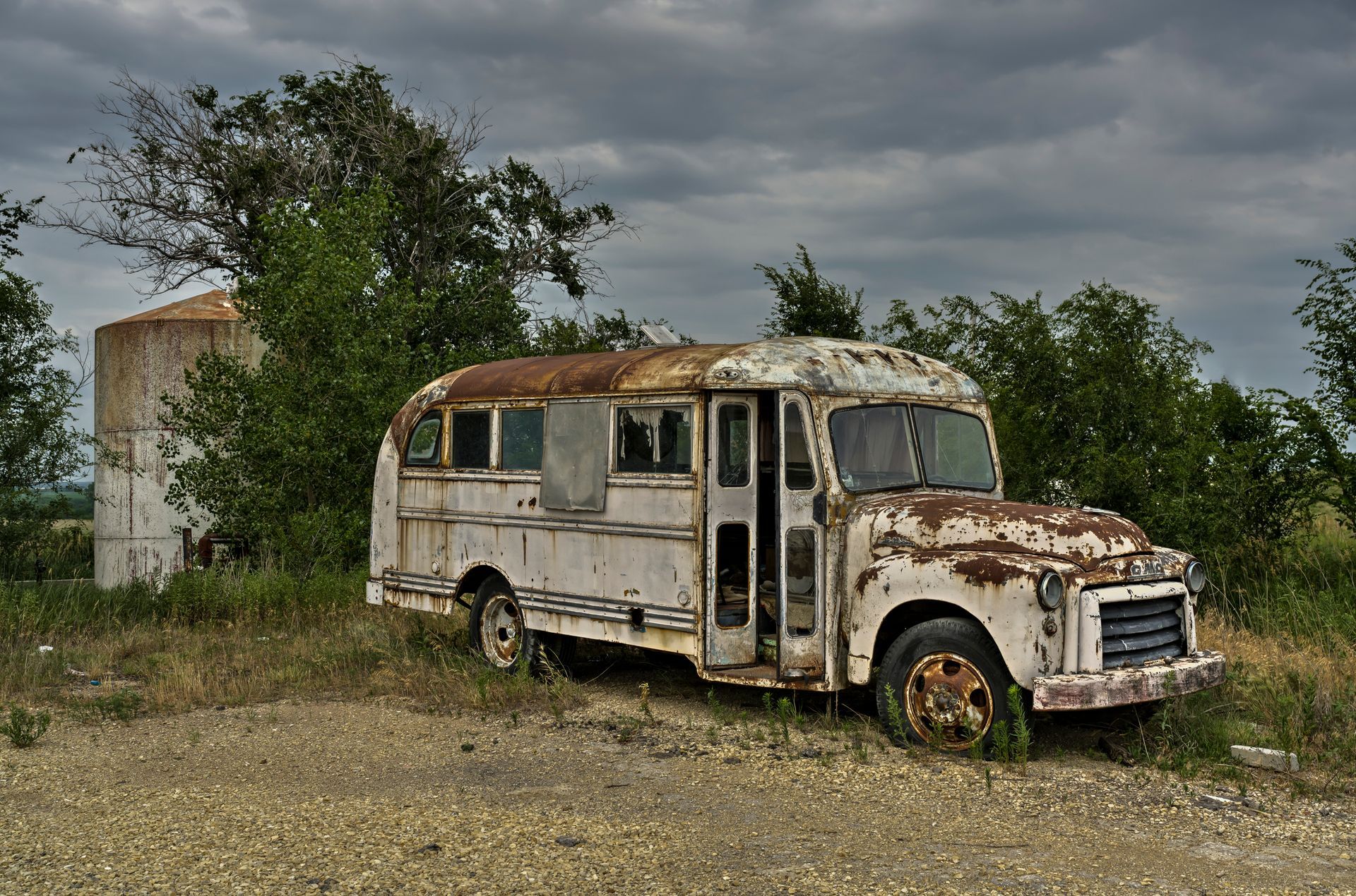 An old rusty school bus is parked in a field.