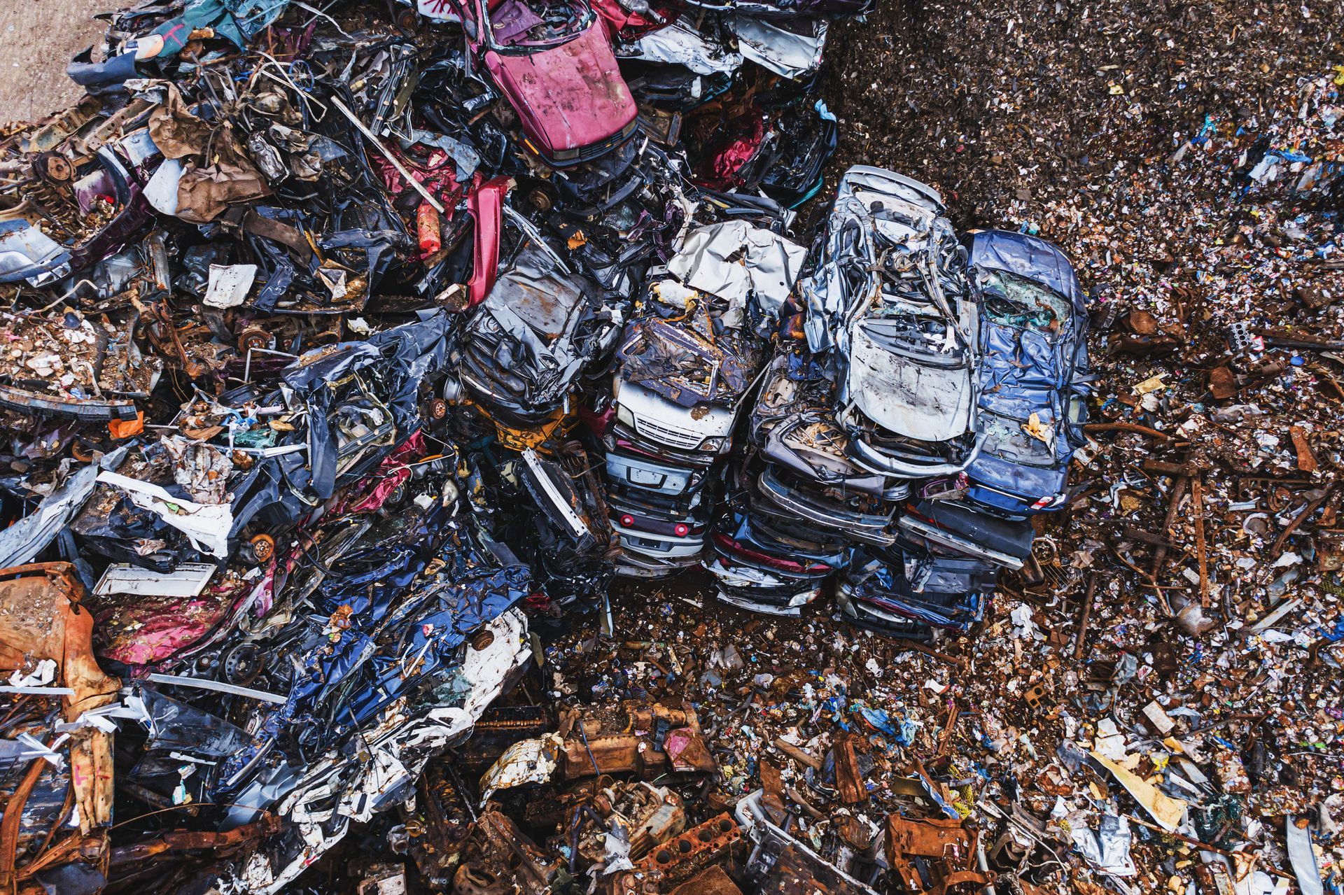 A pile of scrap cars sitting on top of each other on the ground.