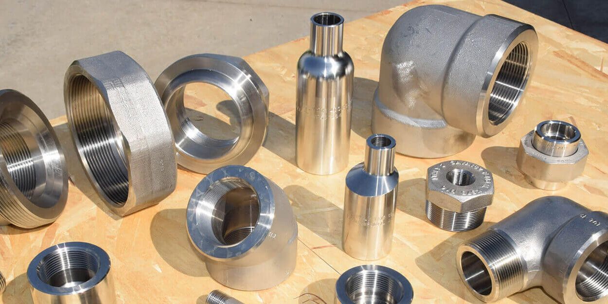 Various stainless steel pipe fittings arranged on a wood surface.