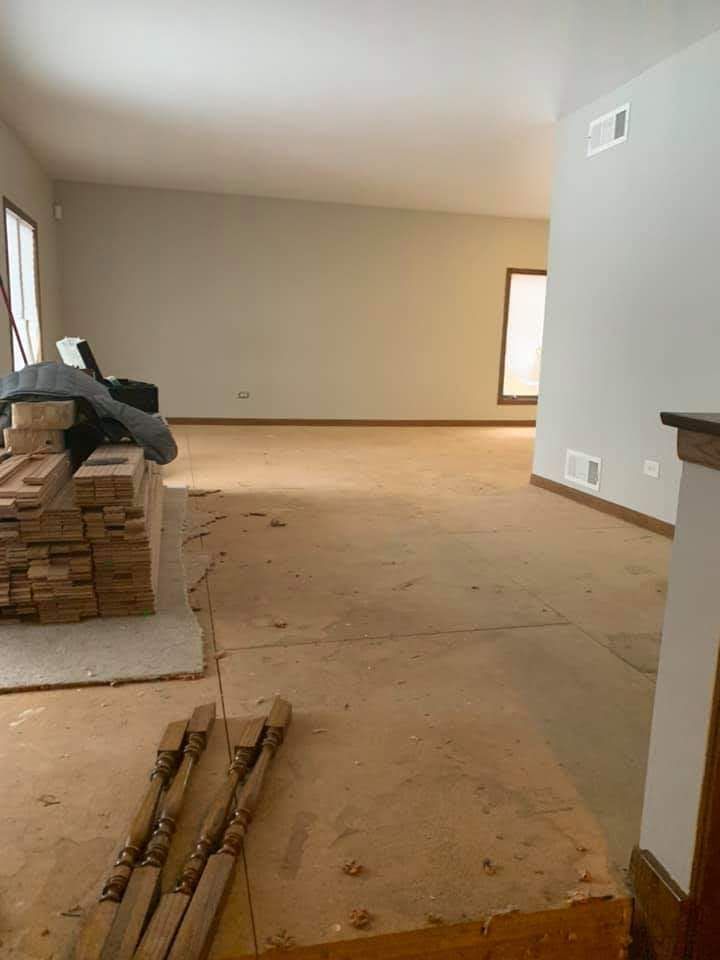 Salón vacío en proceso de renovación, con el contrapiso al descubierto, ladrillos apilados y materiales de construcción.