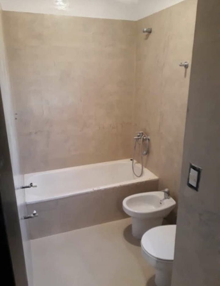 Baño pequeño de color beige con bañera, bidé, inodoro y ducha con grifería de pared.