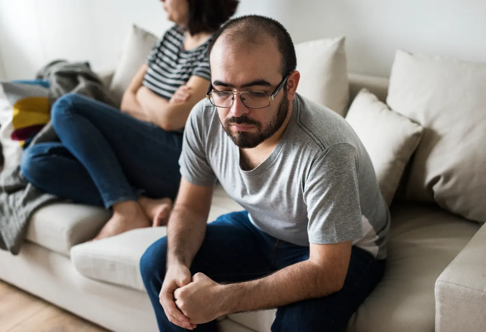 A lady sitting on a couch with hands on her laps.