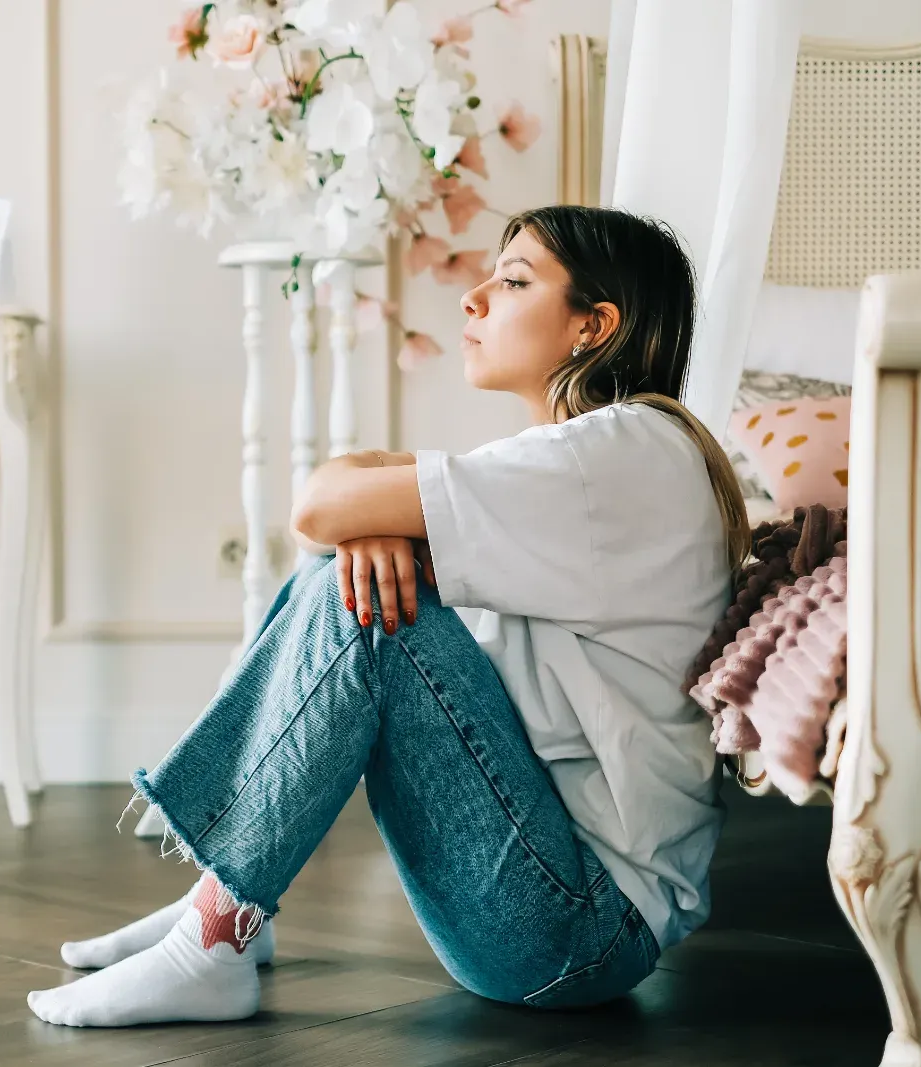 A lady sitting on a couch with hands on her laps.
