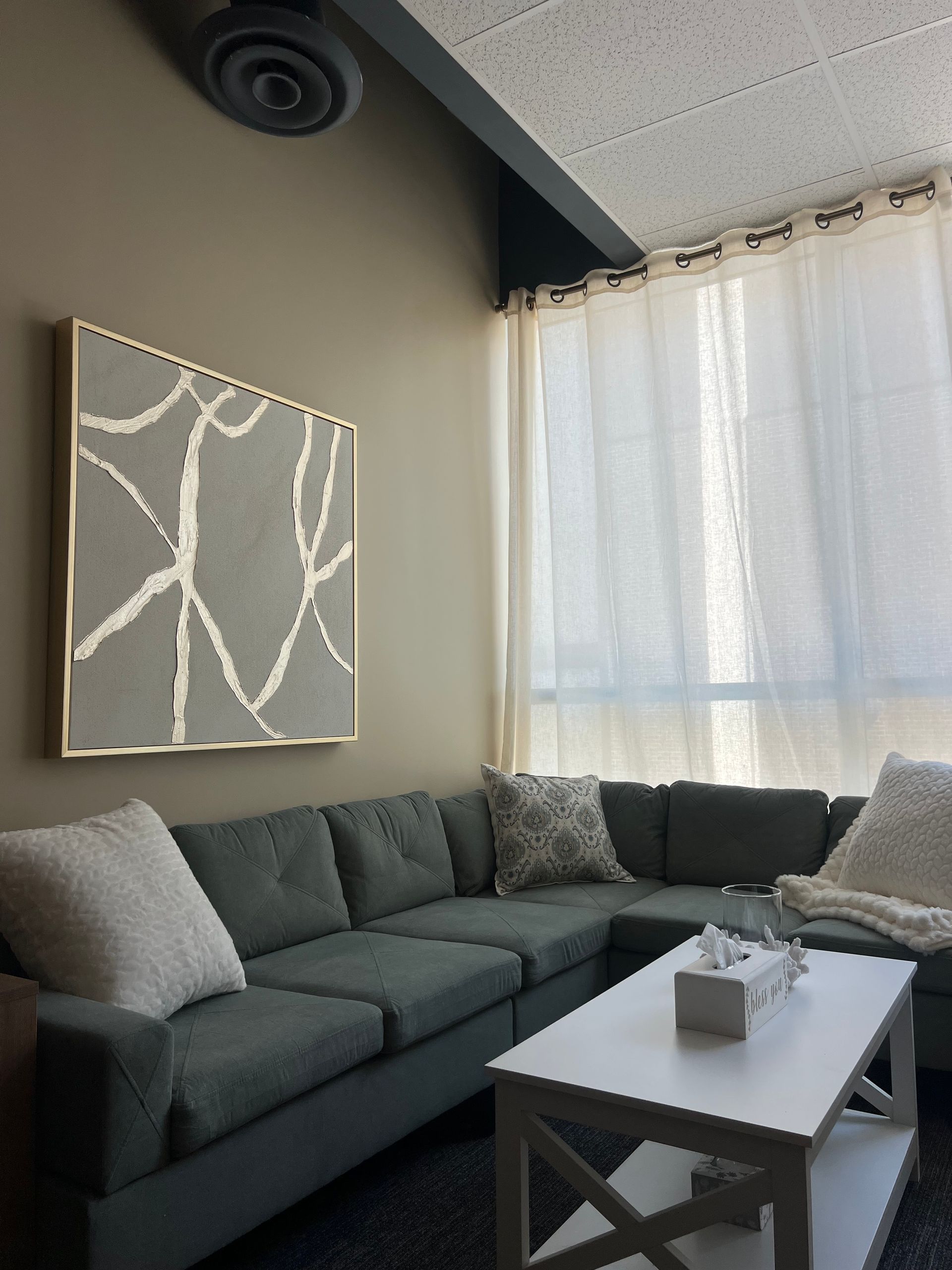 Two people chatting in a cozy living room, smiling by a window and lamp.