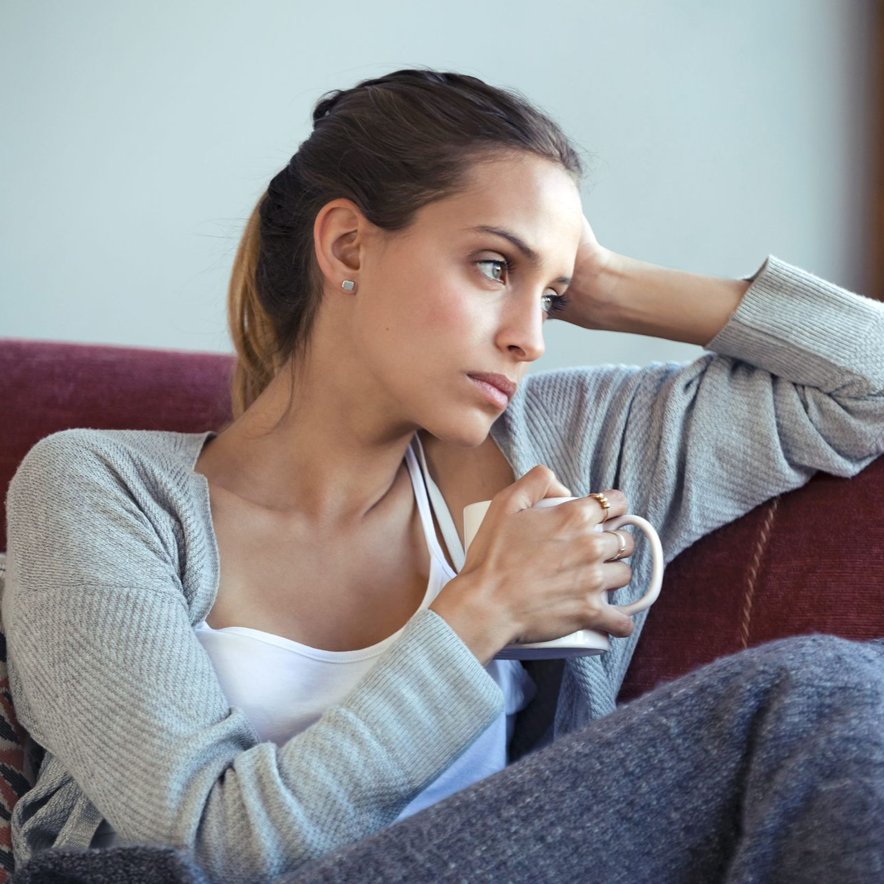 A lady sitting at a cafe with hands on her chest.