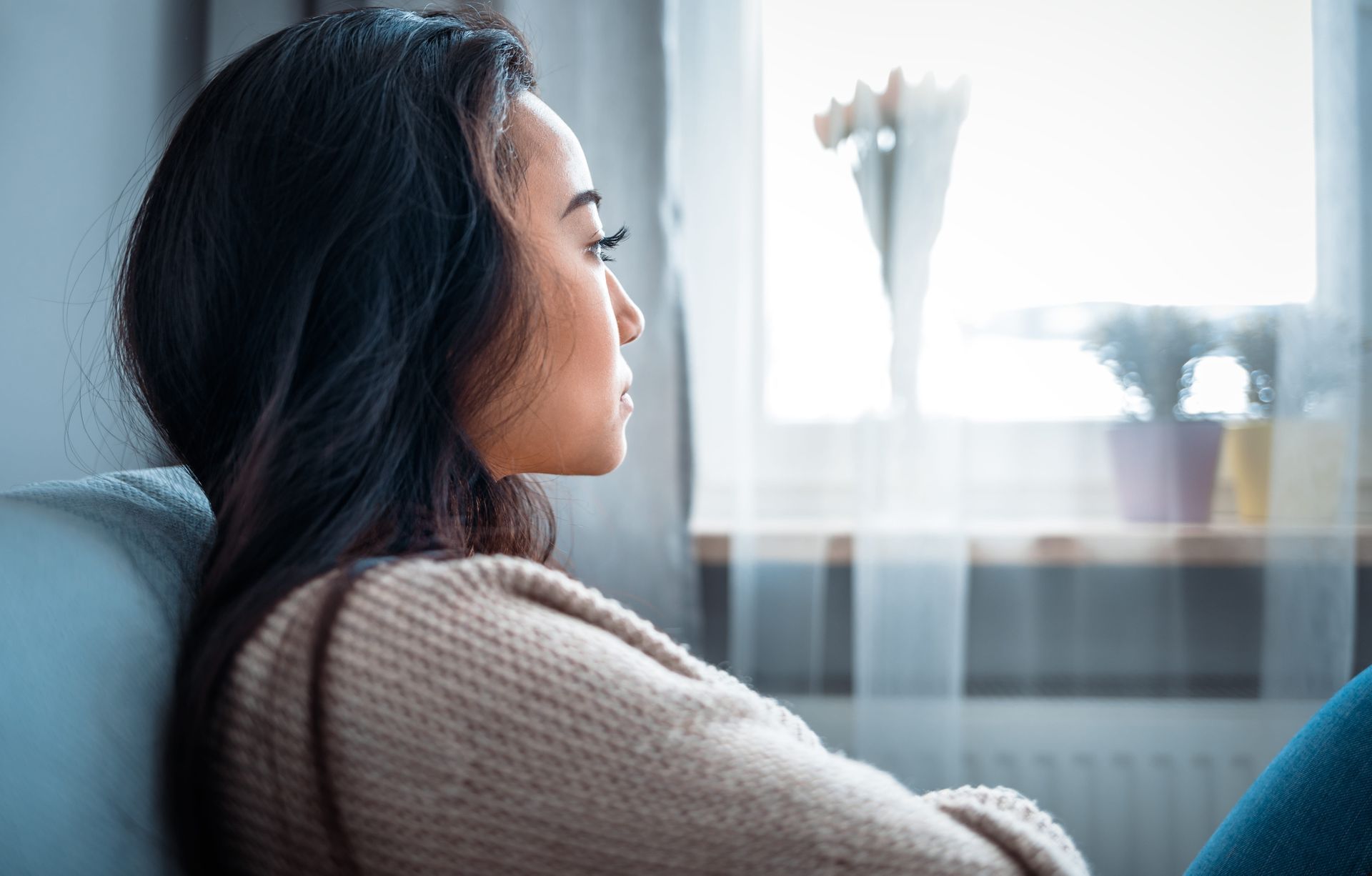 A person looking out a window in quiet reflection, representing the grieving process and healing