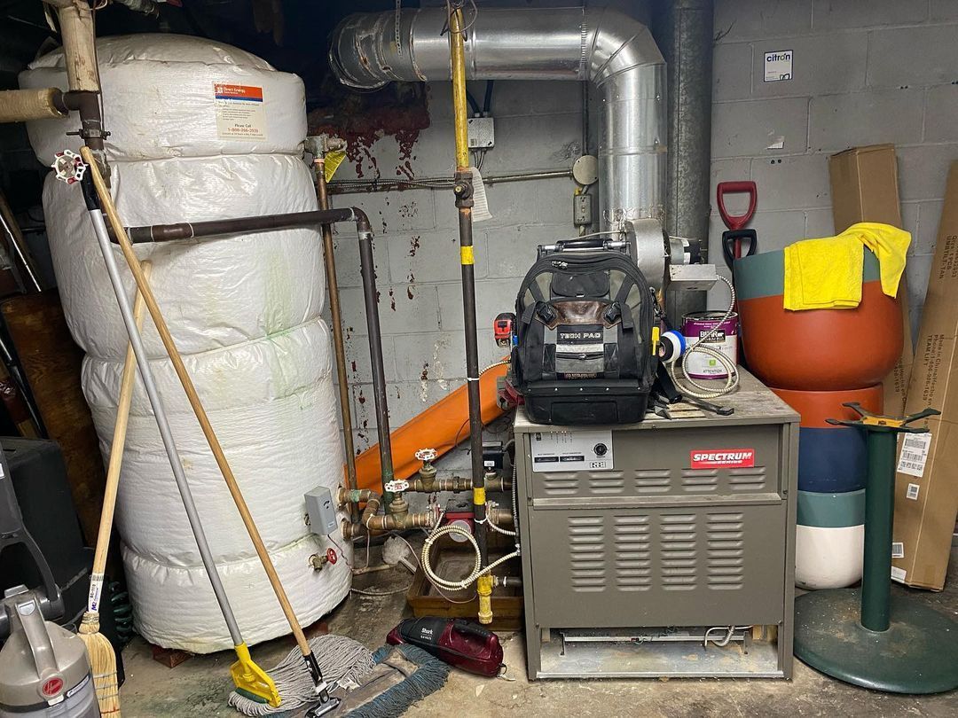 A boiler is sitting in a basement next to a water heater.