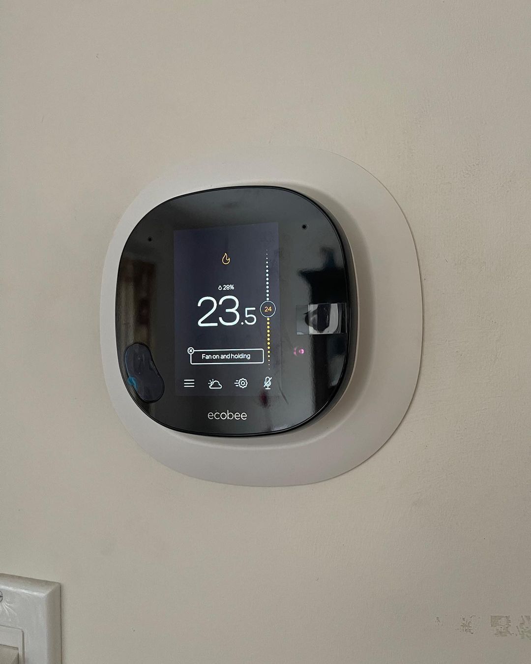 A smart thermostat is mounted on a wall.