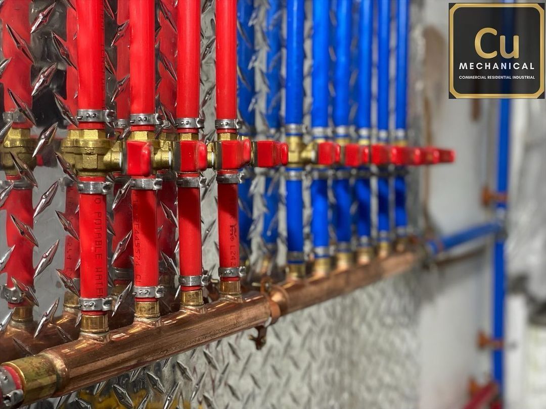 A row of red and blue pipes behind a chain link fence.