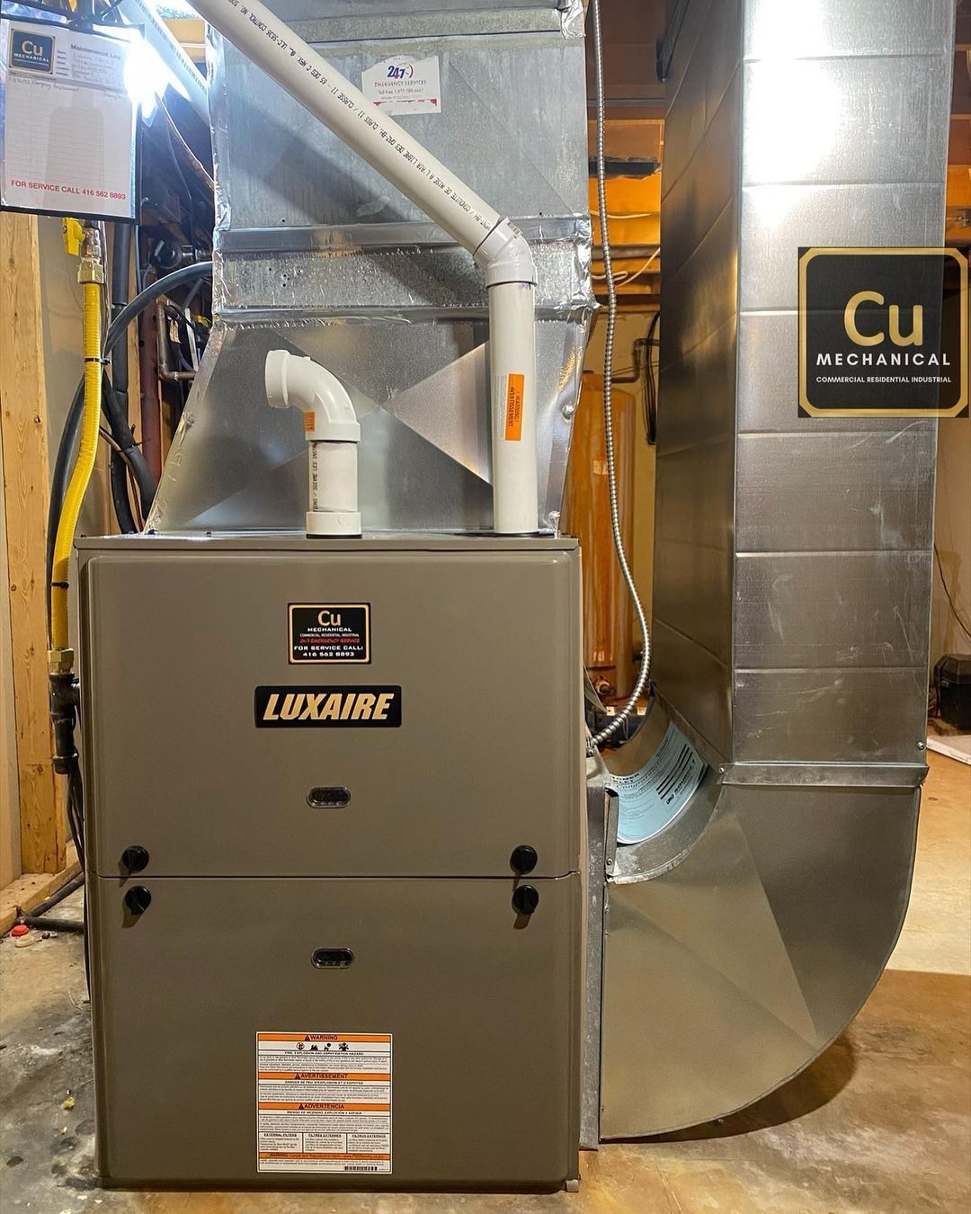 A gas furnace is sitting in a basement next to a sign that says cu.