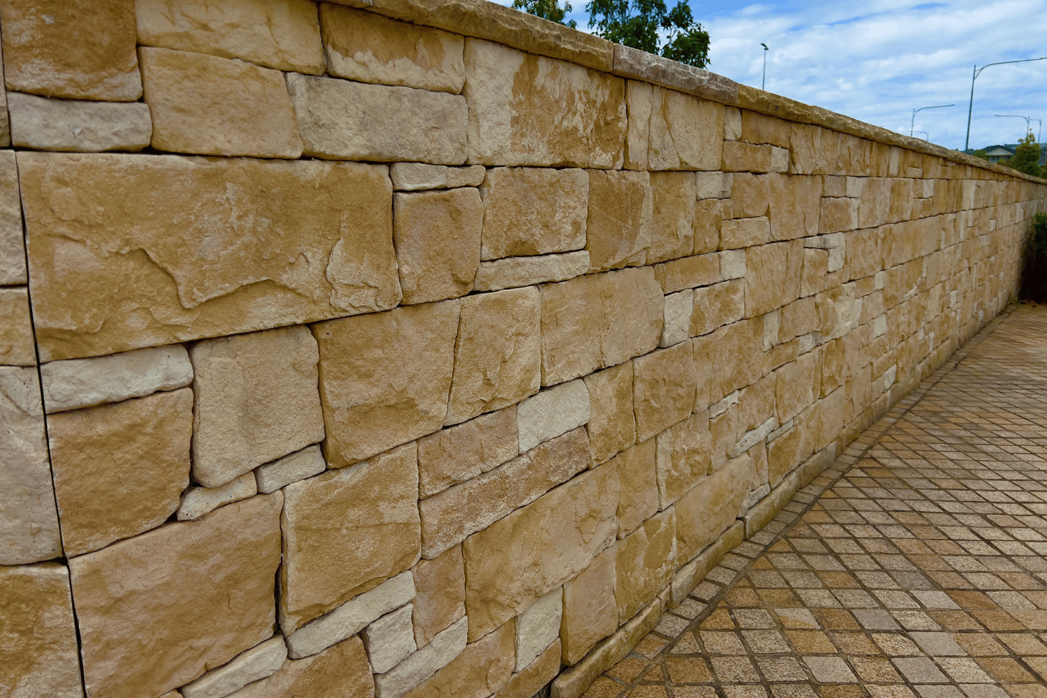 Stone retaining wall beside a paved walkway under a clear sky