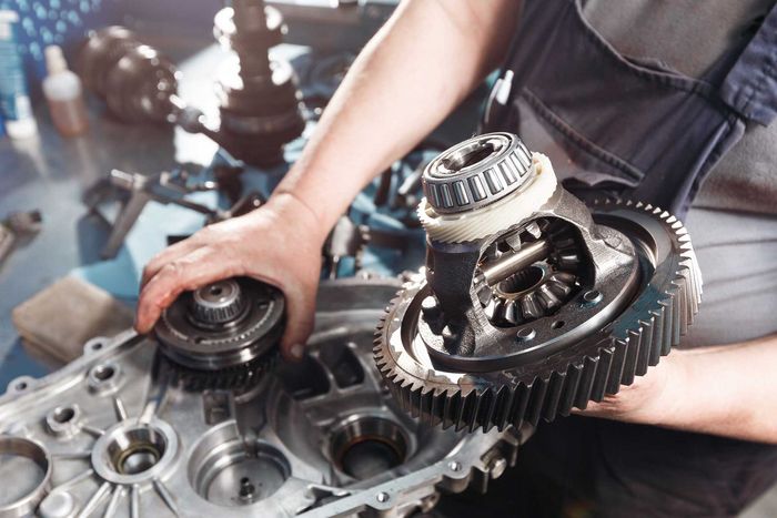 Mechanic assembling car transmission gears on a workbench with tools nearby Mechanic assembling car transmission gears on a workbench with tools nearby
