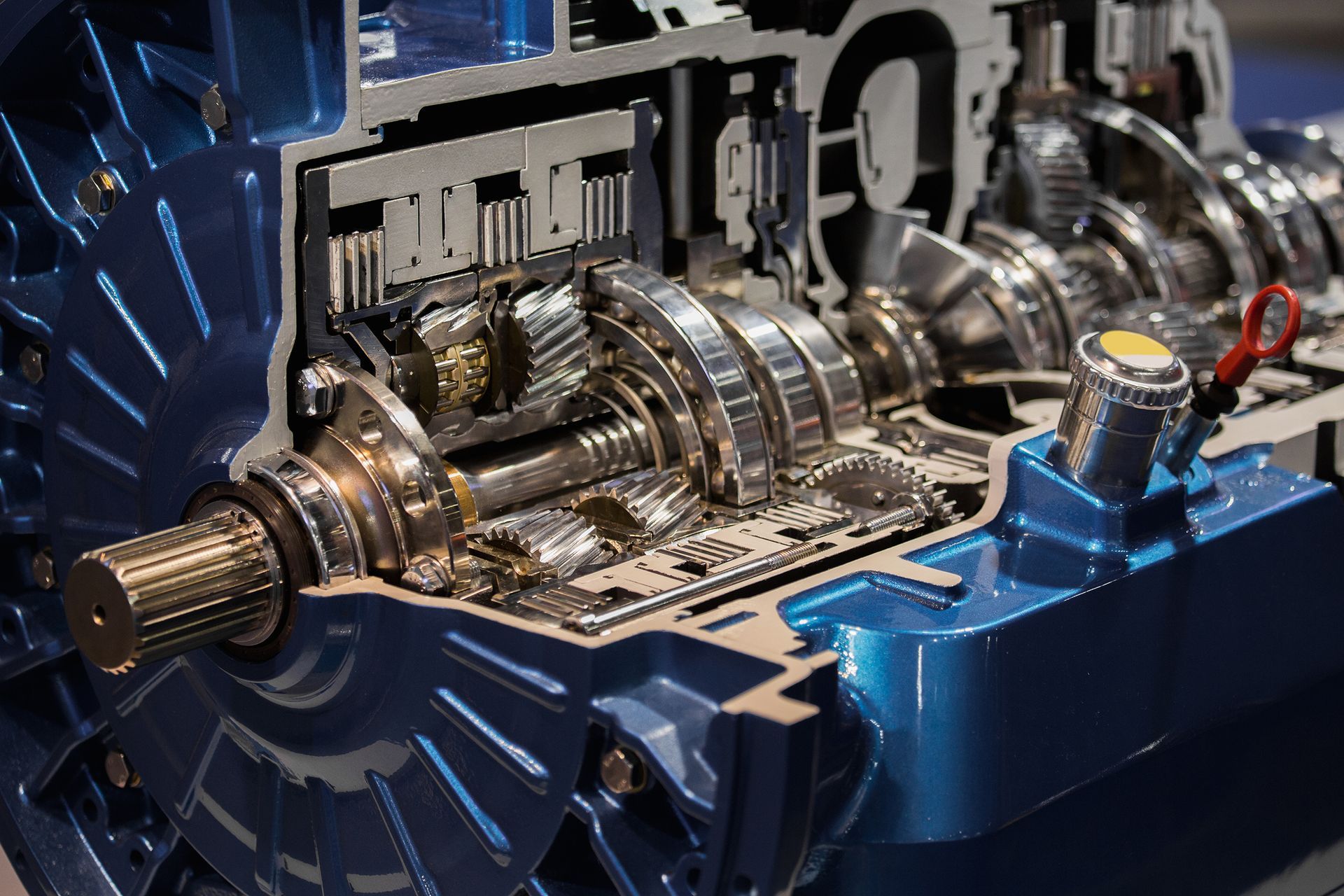Close-up of a blue industrial machine with exposed metal gears and shafts operating inside.