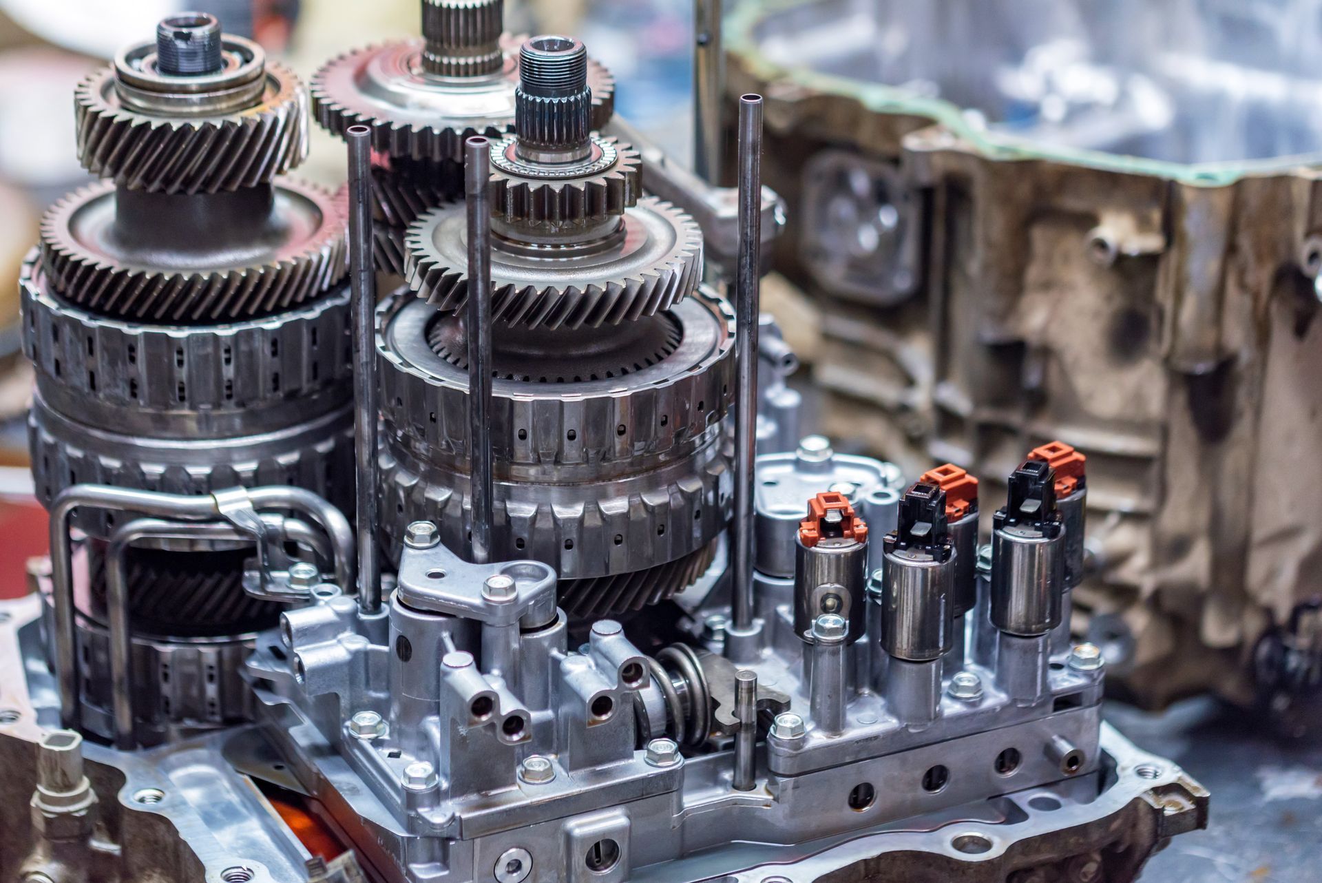 Close-up of a complex metal gearbox assembly with gears and shafts on a workbench