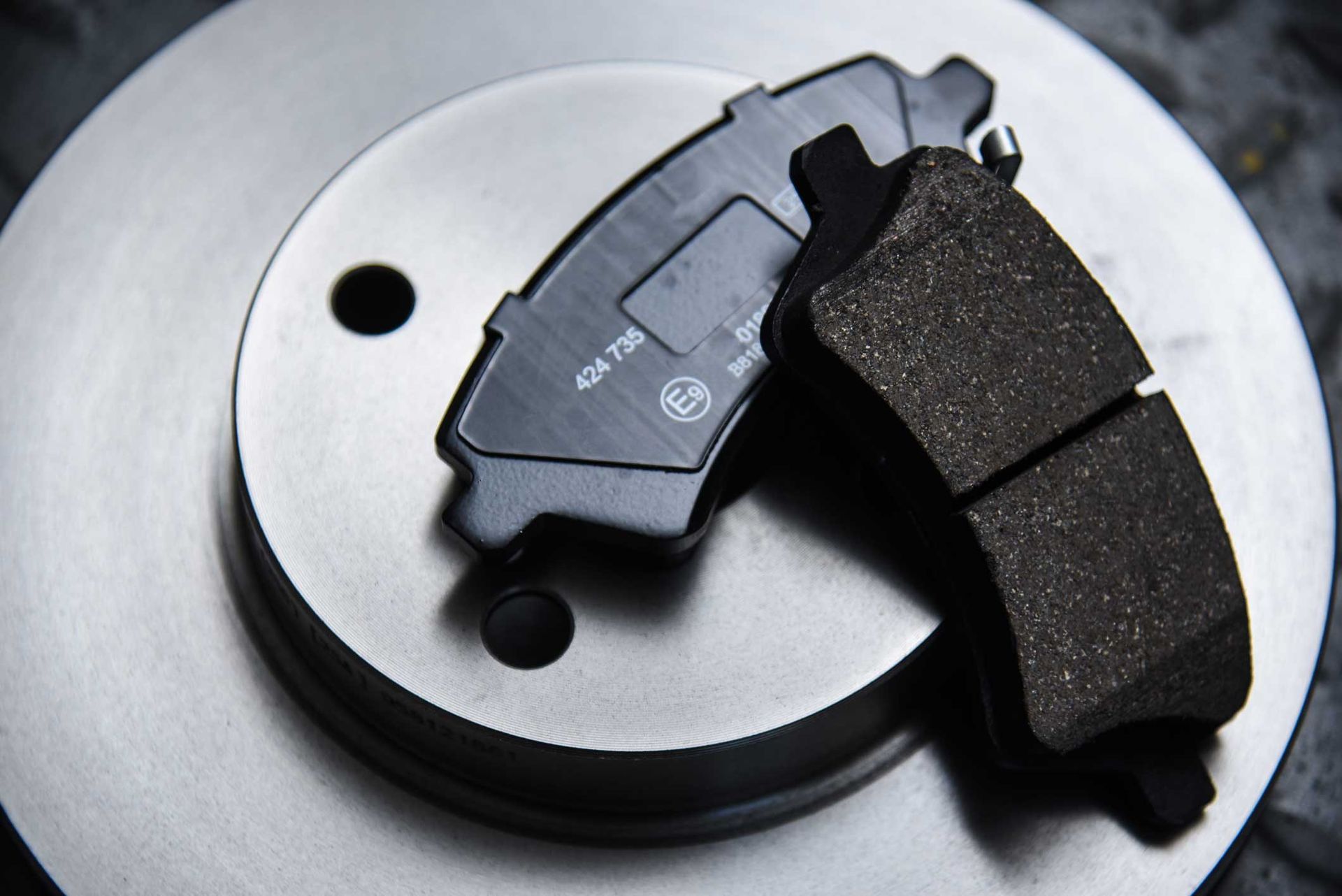 Car brake pad on a silver brake rotor, close-up product shot