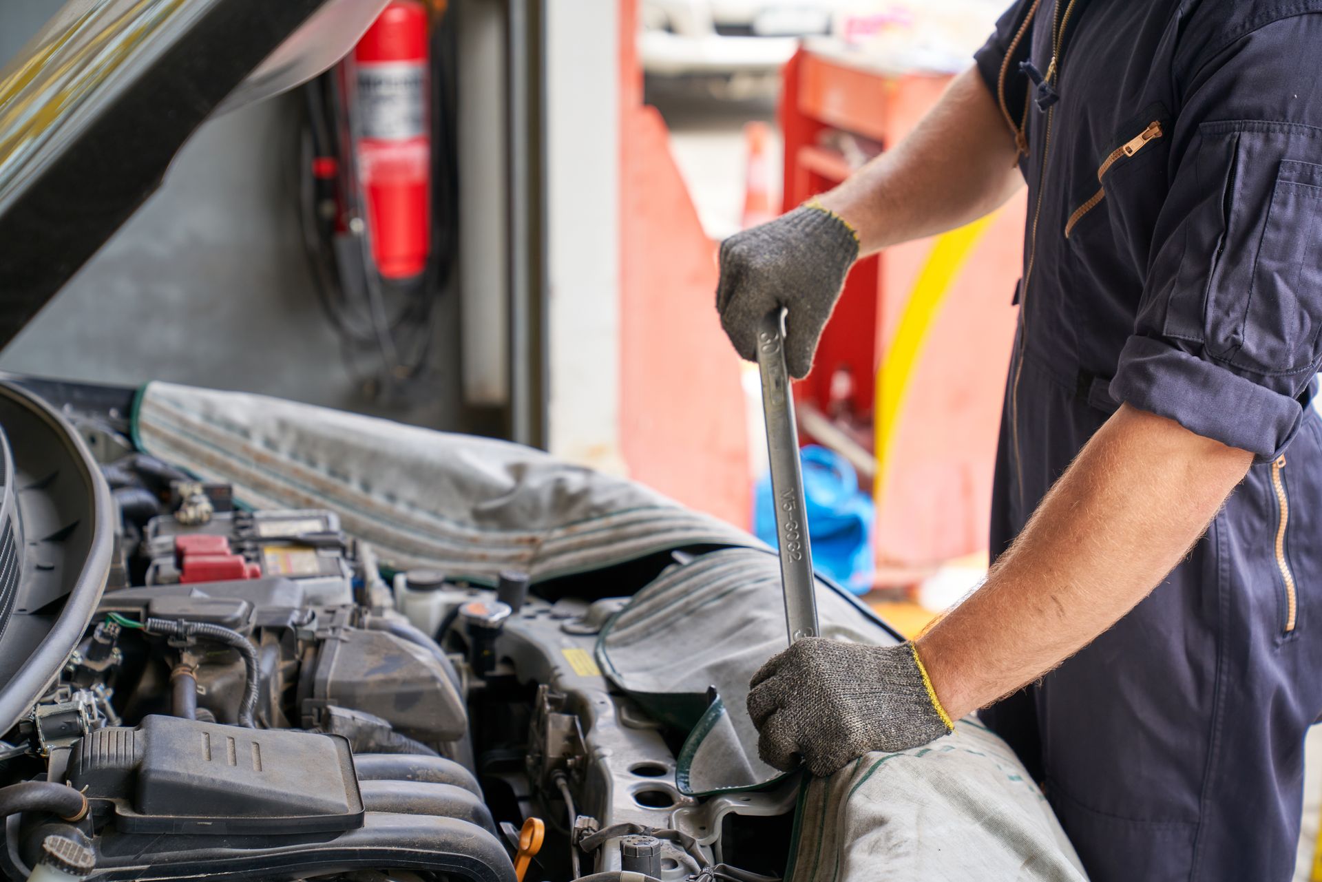 Mechanic using a wrench on a car engine in a repair shop