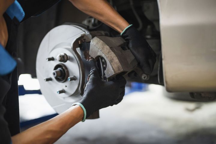 Mechanic replacing a car brake rotor with gloved hands Mechanic replacing a car brake rotor with gloved hands