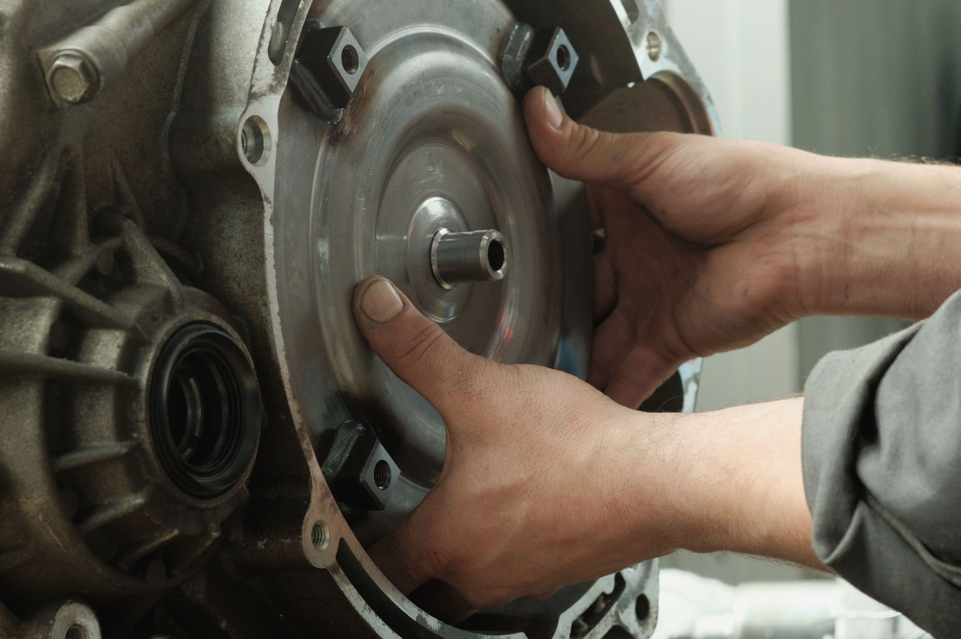 Hands installing a circular metal part on machinery in a workshop