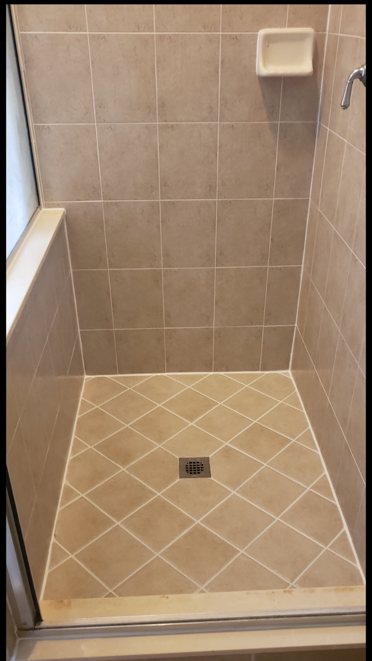 Tan tiled shower with diamond-patterned floor and a soap dish.