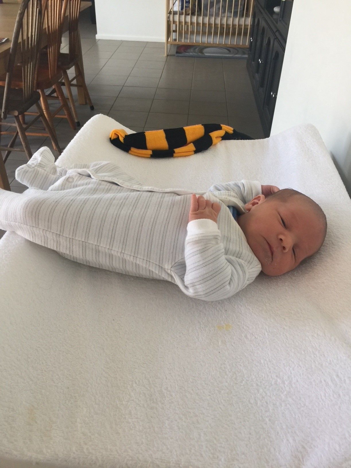 A baby is laying on a changing table next to a stuffed animal.