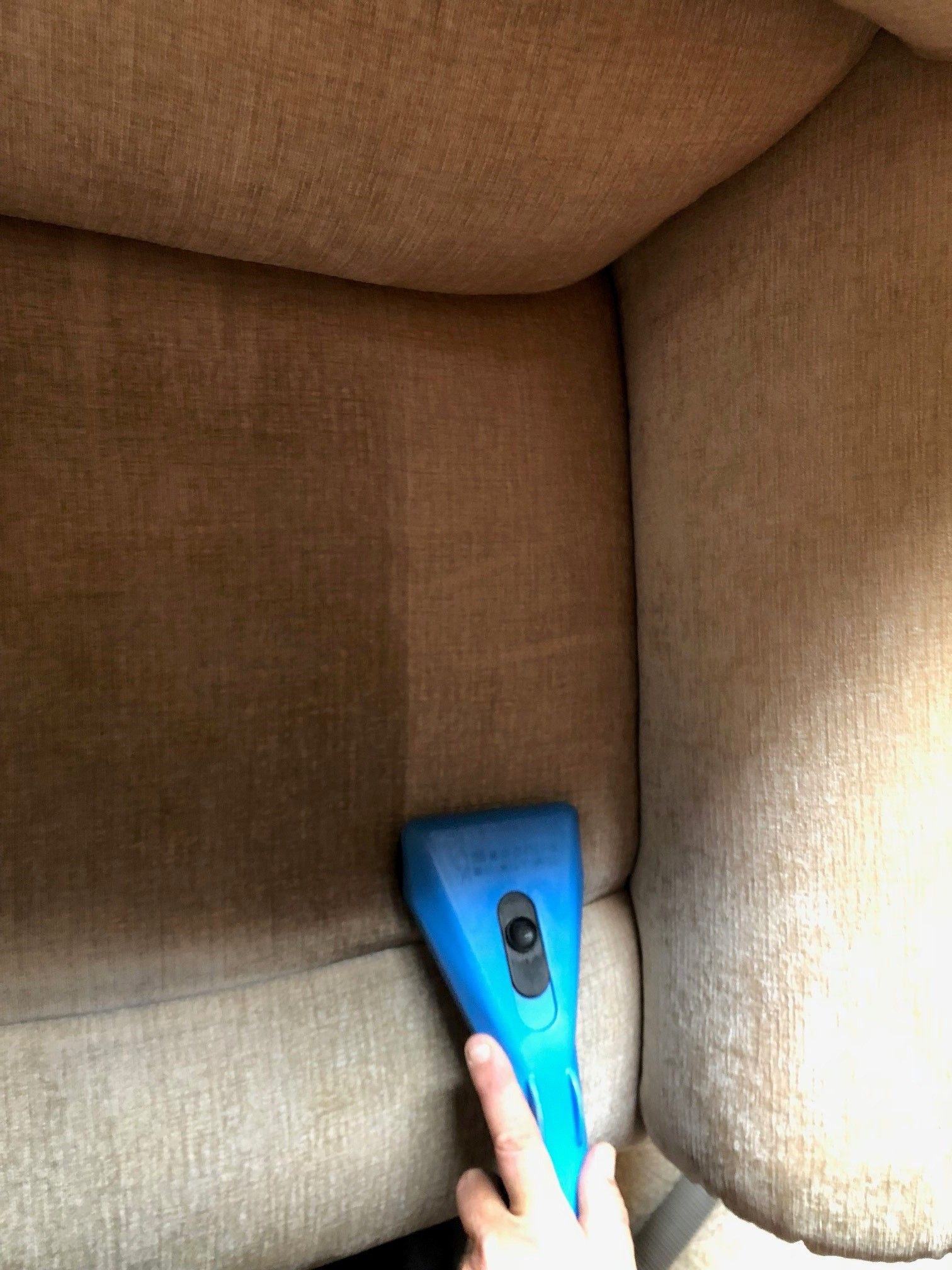 A blue upholstery cleaner is being used to clean a couch.