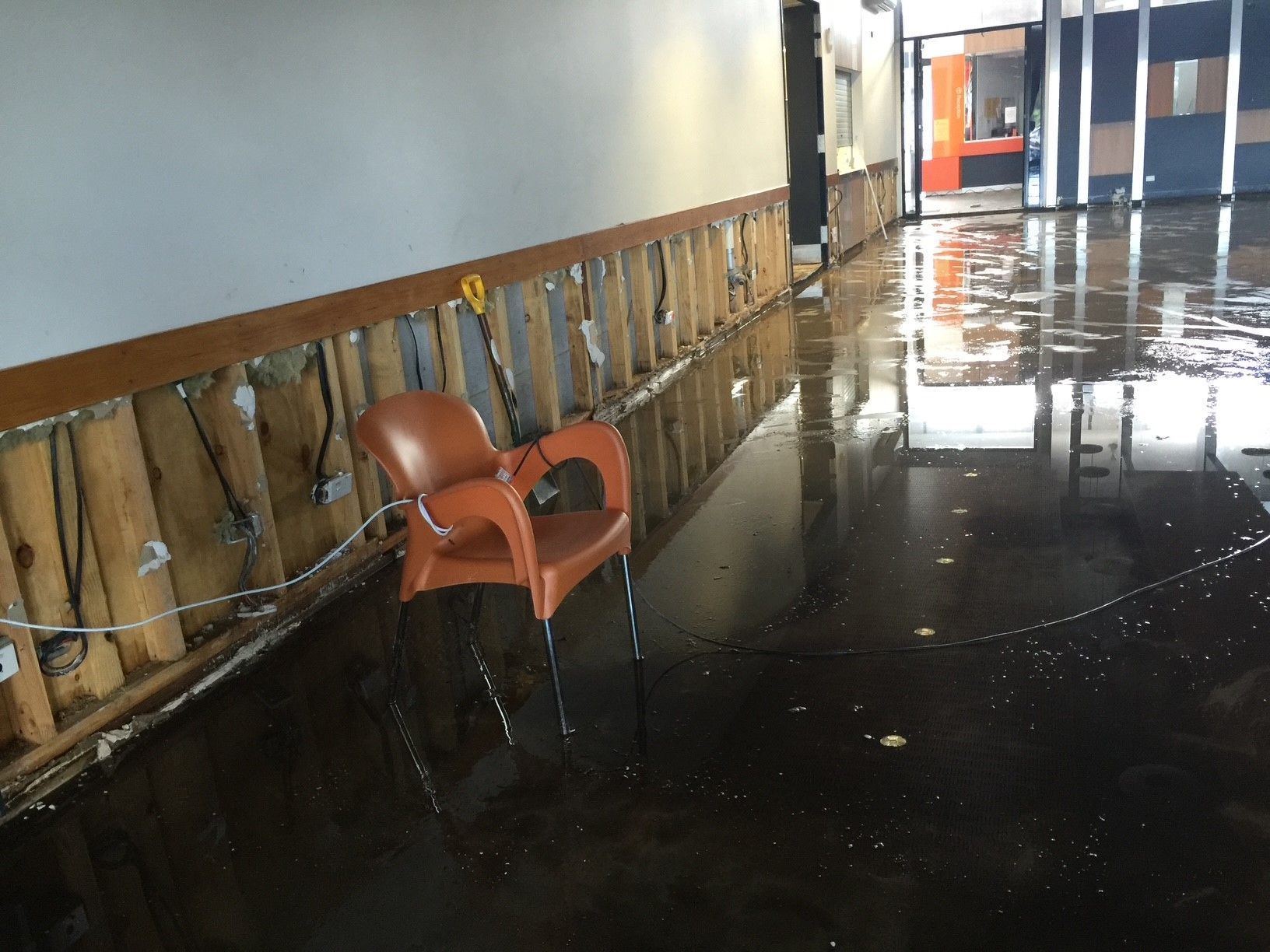 An orange chair is sitting in a flooded hallway