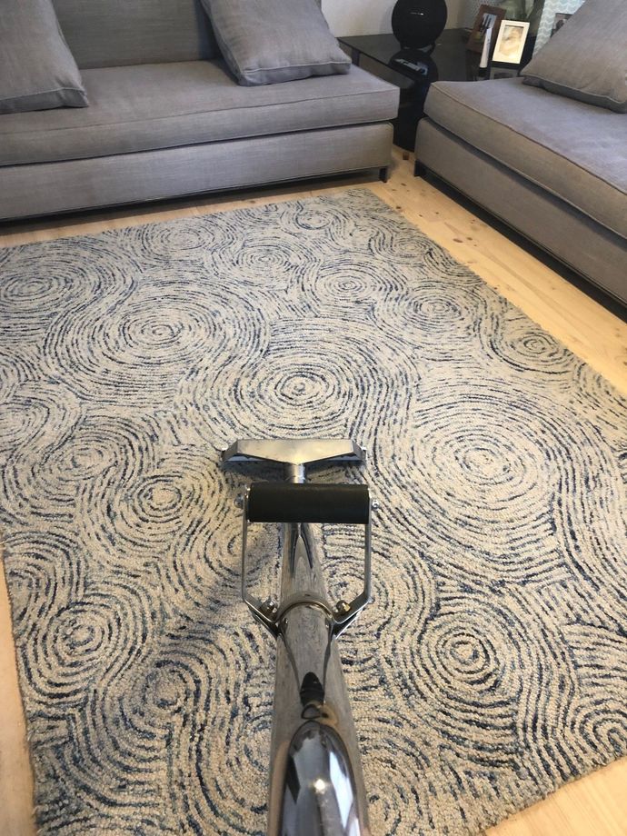 A woman is using a vacuum cleaner to clean a carpet in a living room.