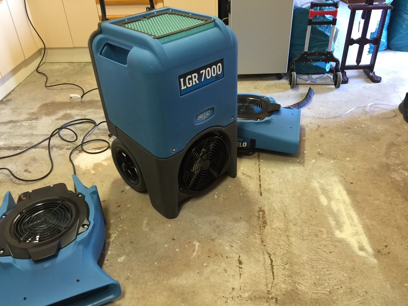 A blue dryer is sitting on the floor in a room.