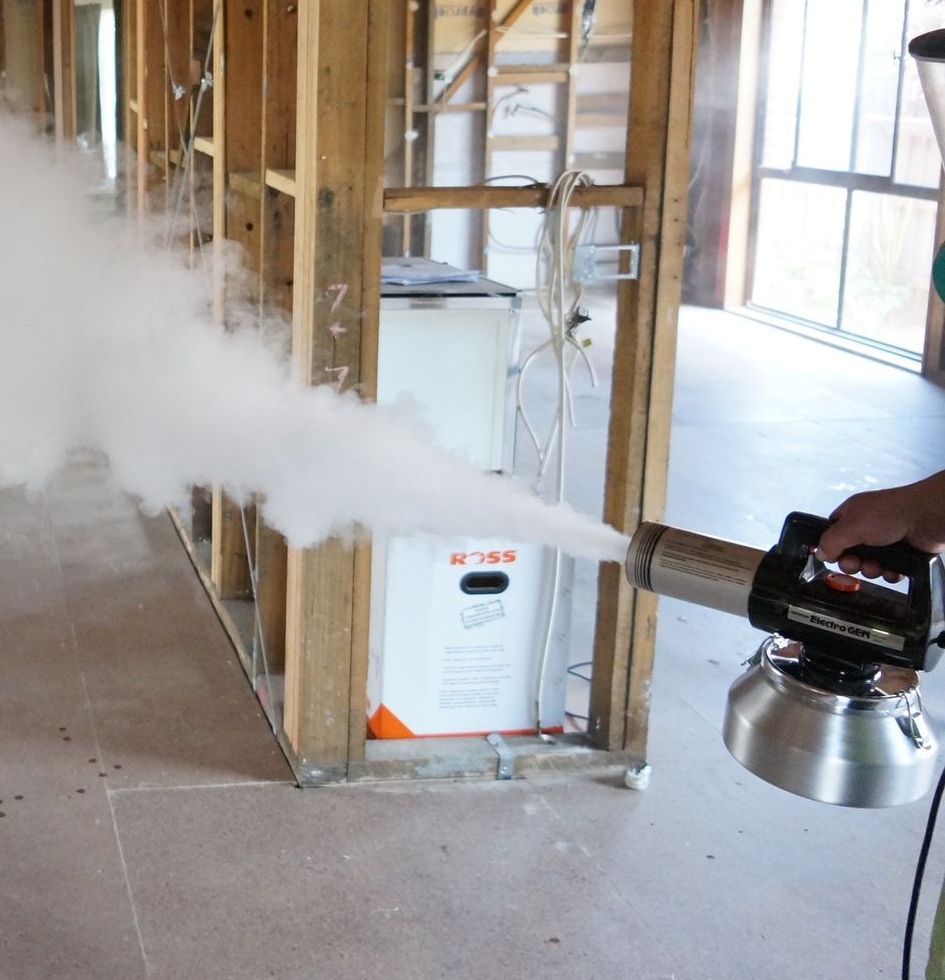 A person is spraying a room with a fog machine