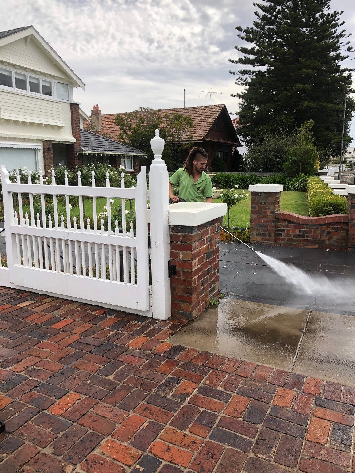 A man is using a high pressure washer to clean a patio.