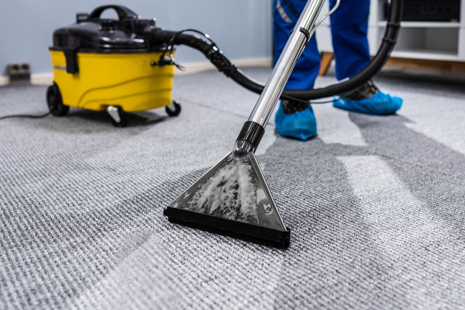 A person cleaning a carpet with a vacuum cleaner