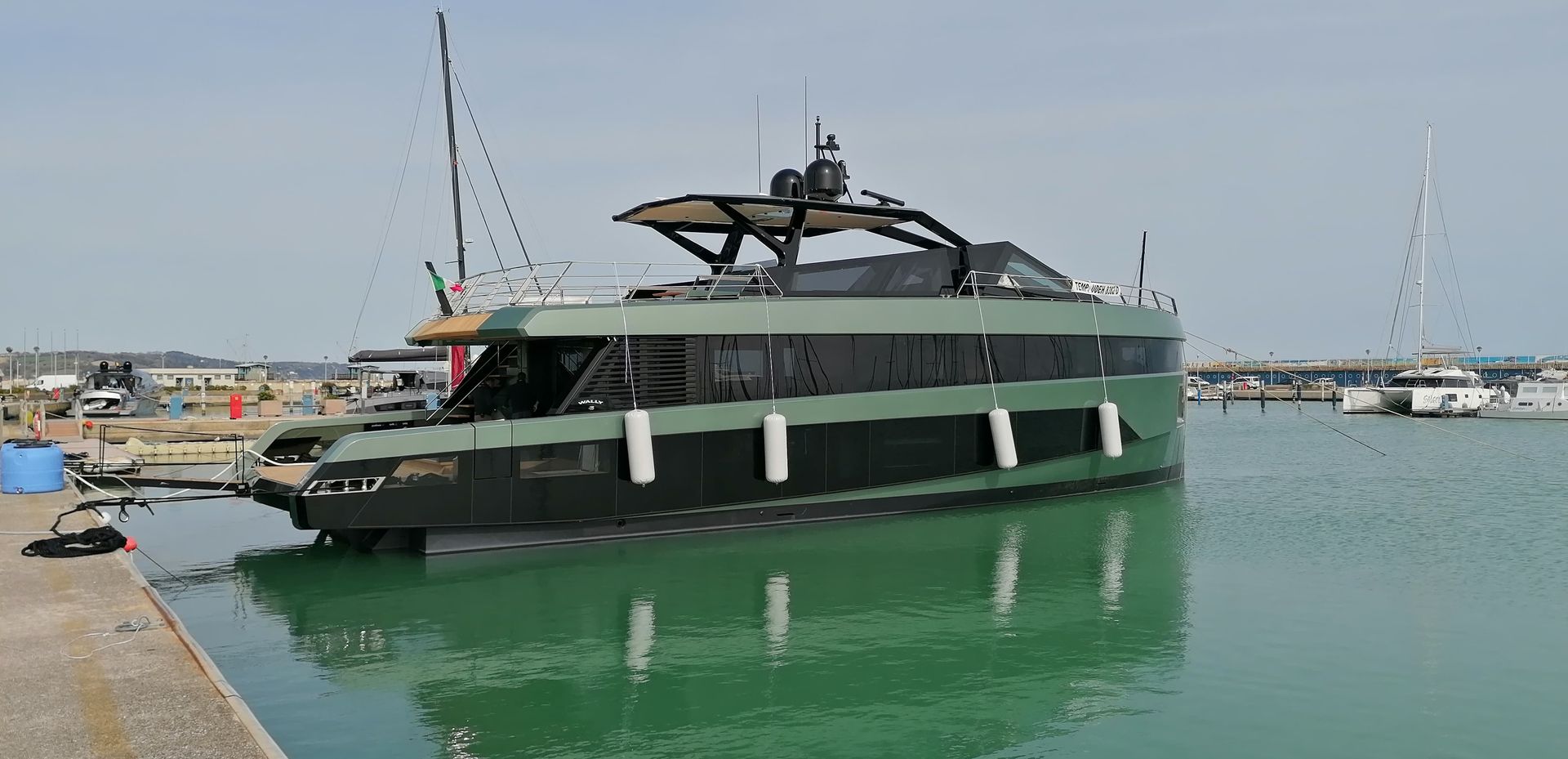 Uno yacht verde e nero attraccato su un molo si riflette nell'acqua turchese.