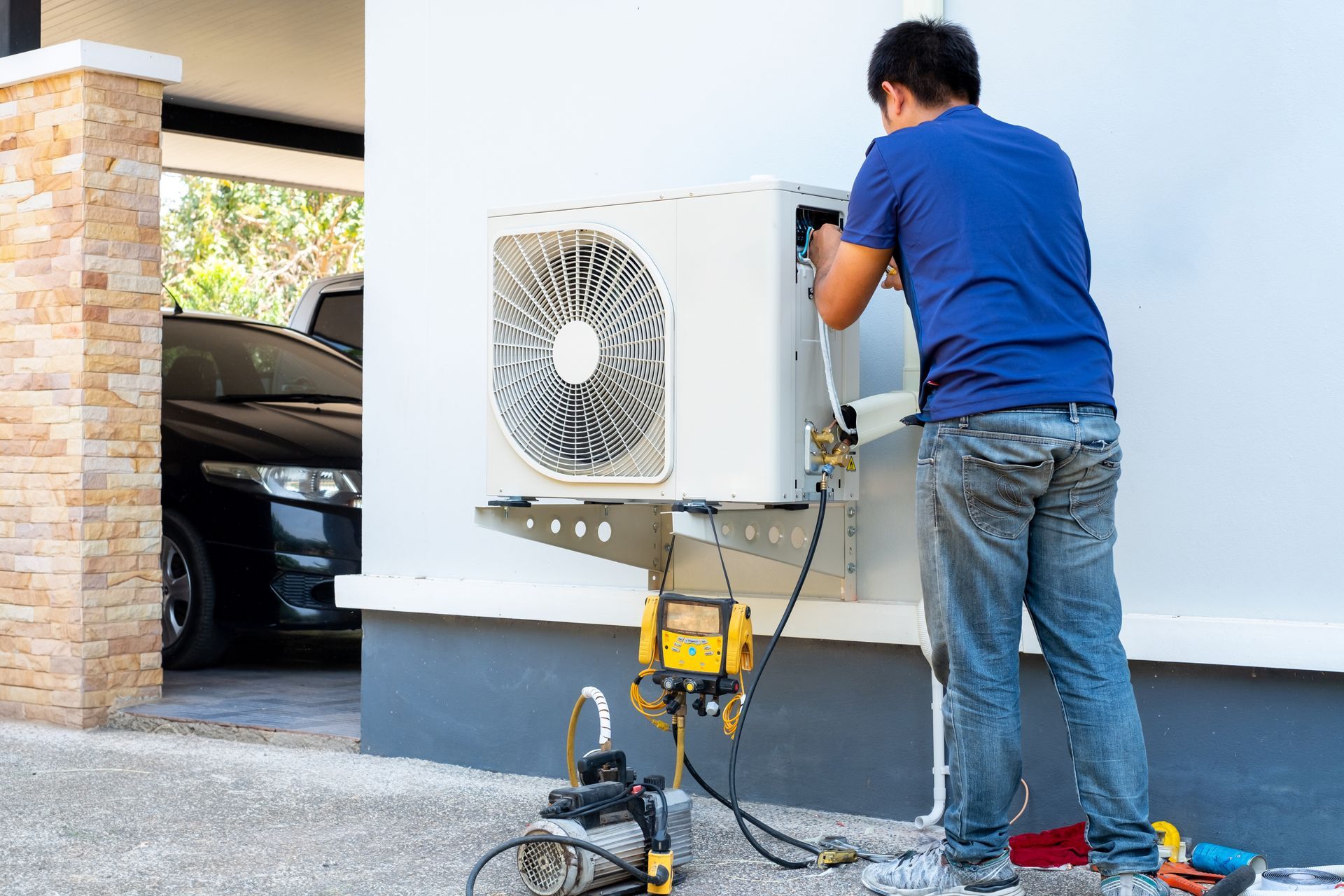 Person servicing a white wall-mounted air conditioning unit, removing the filter.