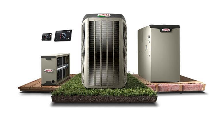 Three outdoor air conditioning units on a concrete pad with grass in the foreground.