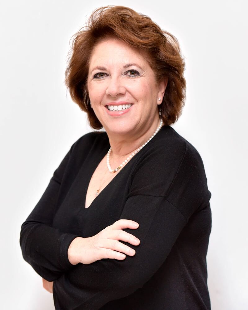 Donna sorridente con top nero e braccia incrociate su sfondo bianco