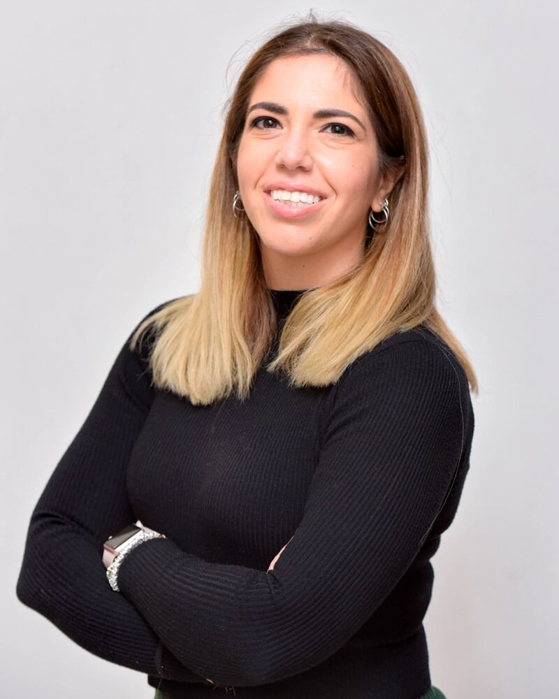 Persona sorridente con le braccia incrociate, con indosso una maglietta nera, su sfondo grigio chiaro.