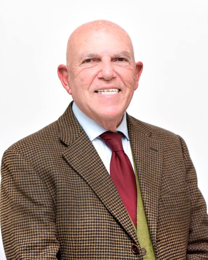 Uomo calvo sorridente con giacca di tweed marrone e cravatta rossa su sfondo bianco