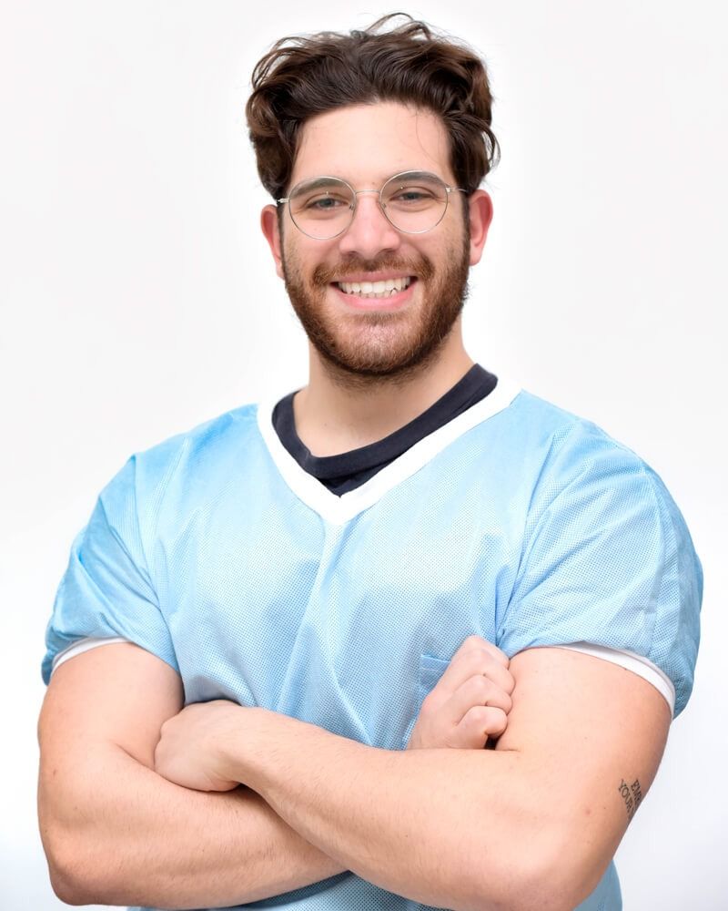 Persona sorridente in camice blu con le braccia incrociate su sfondo bianco