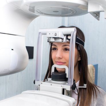 Una donna all'interno di un apparecchio per radiografie dentali durante un esame a raggi X.