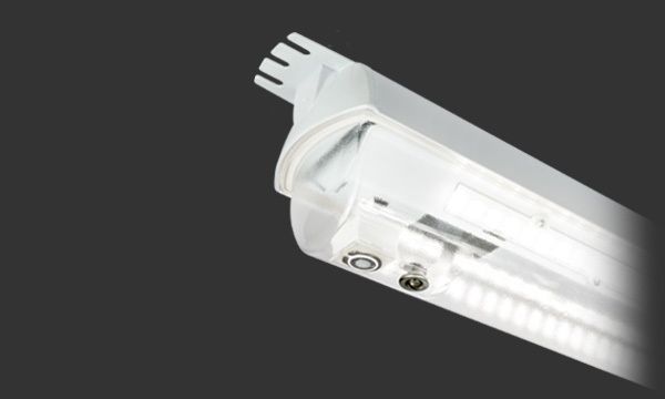 Hvit LED-lysarmatur med monteringsbrakett, kontakter og klart objektiv på mørk bakgrunn.