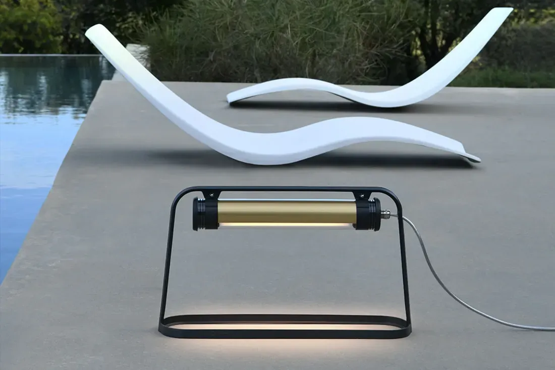 Moderne utendørslampe og buede hvite sjeselonger ved et basseng.