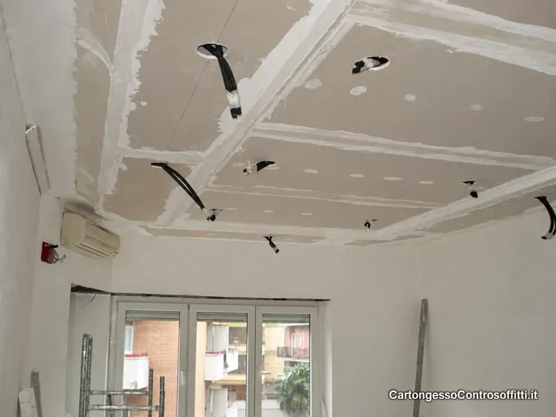Controsoffitto geometrico in cartongesso con fasce, giunti stuccati e cavi predisposti.